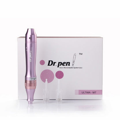 Ružové Dr. Pen Ultima M7 microneedling-pero stojí pred bielym balením produktu, spolu s dvoma priehľadnými ihlovými hlavicami.